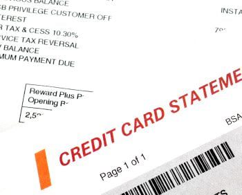 A close-up view of a printed credit card statement with a barcode, transaction details, payment history, and the words "CREDIT CARD STATEMENT" in red.