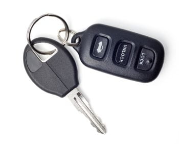 A metallic car key and a black car remote, featuring three buttons defaulting to trunk access, unlocking, and locking.