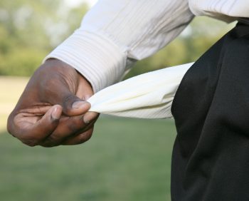 A person pulls out an empty pocket from their black pants while standing outside, perhaps pondering the federal taxes owed.