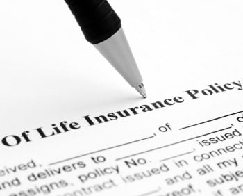 Close-up of a pen lying on a life insurance document showing part of the title and some blank fields to be filled out.