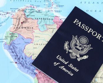 A United States passport rests on a map of South America, partially covering Ecuador, Colombia, and Venezuela, evoking the spirit of travel.