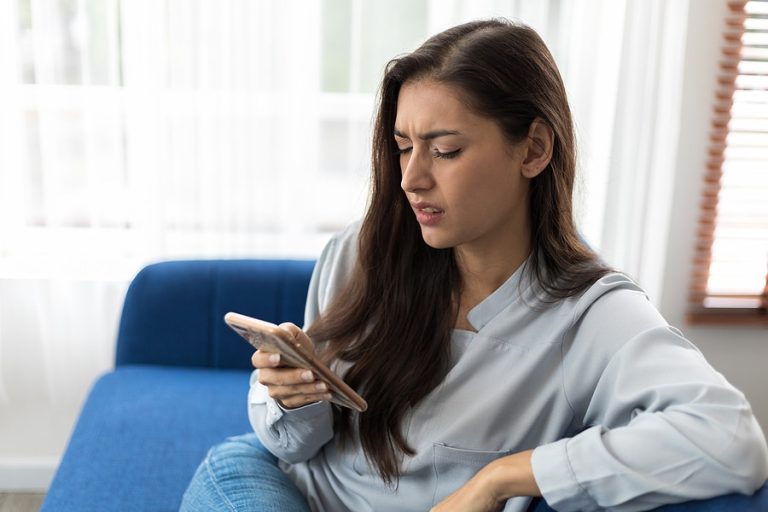 Woman reads bad news in mobile message. Female sad looking at smart phone feels shocked. Business woman worried from investment losses. Customers are not happy with the internet connection speed.