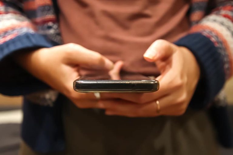 Closeup scrolling phone. Defocus female hand holding black phone. Close up of a woman using mobile smartphone. Millennial style. Social media. Out of focus.