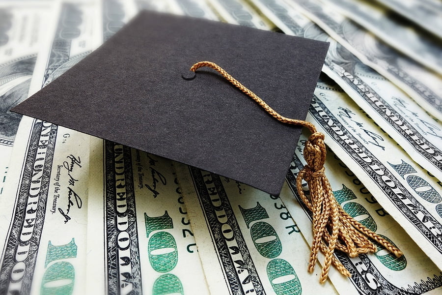 Mini graduation mortar board cap on money -- education cost or scholarship concept