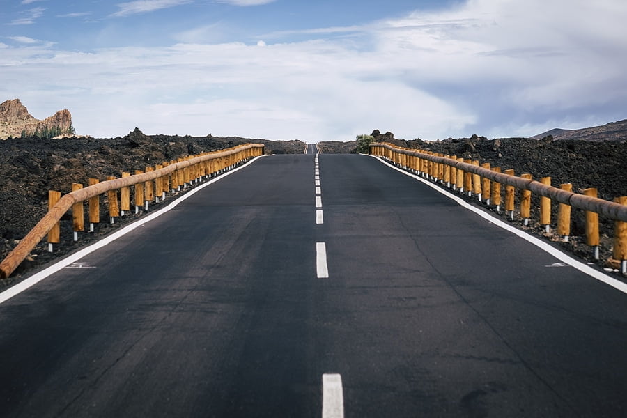 long way road of asphalt with white straight line in the middle and infinite direction and travel distance concept. asphalt and mountains around for traveler and adventure concept. no cars no people long-distance move