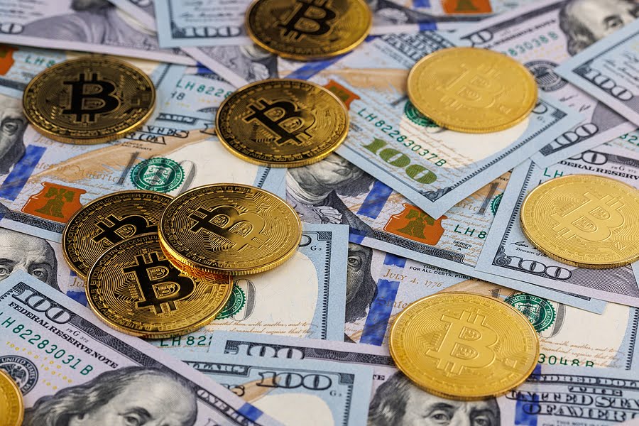 yellow bitcoin coins scattered over US dollar paper banknotes, cryptocurrency and fiat money exchange concept, closeup with selective focus