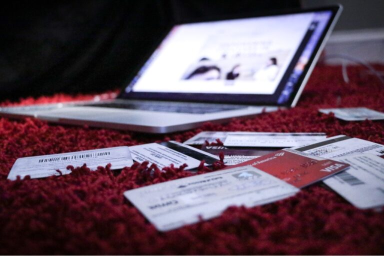 A laptop rests on a red carpet, surrounded by scattered credit cards, serving as the perfect setup for a digital financial planner.