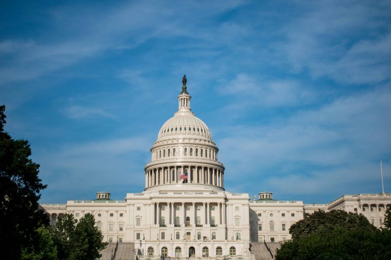 The United States Capitol building under a clear blue sky, with trees partially framing the structure, inspires the careful planning and credit management that a financial planner would admire.