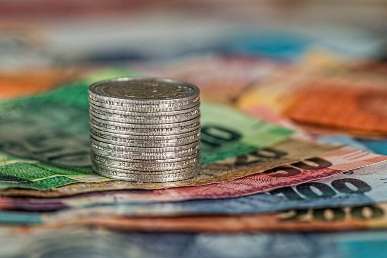 A meticulously organized stack of silver coins rests atop various colored banknotes, embodying the precision and strategy of a financial planner.