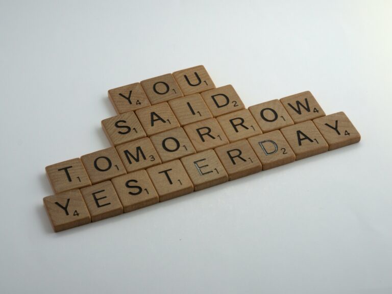 Scrabble tiles on a white surface spell out "YOU SAID TOMORROW YESTERDAY," a playful reminder from your financial planner to stay on budget.