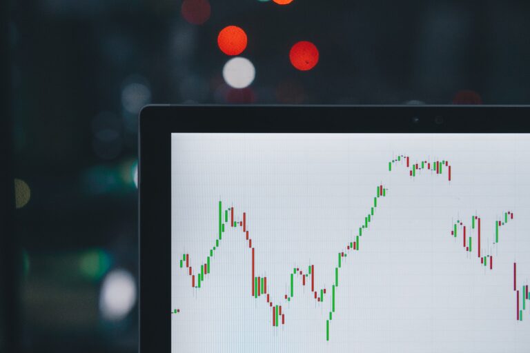 A computer screen displaying a financial chart with fluctuating red and green candlesticks, analyzed by a keen financial planner, set against a blurred background with bokeh lights.