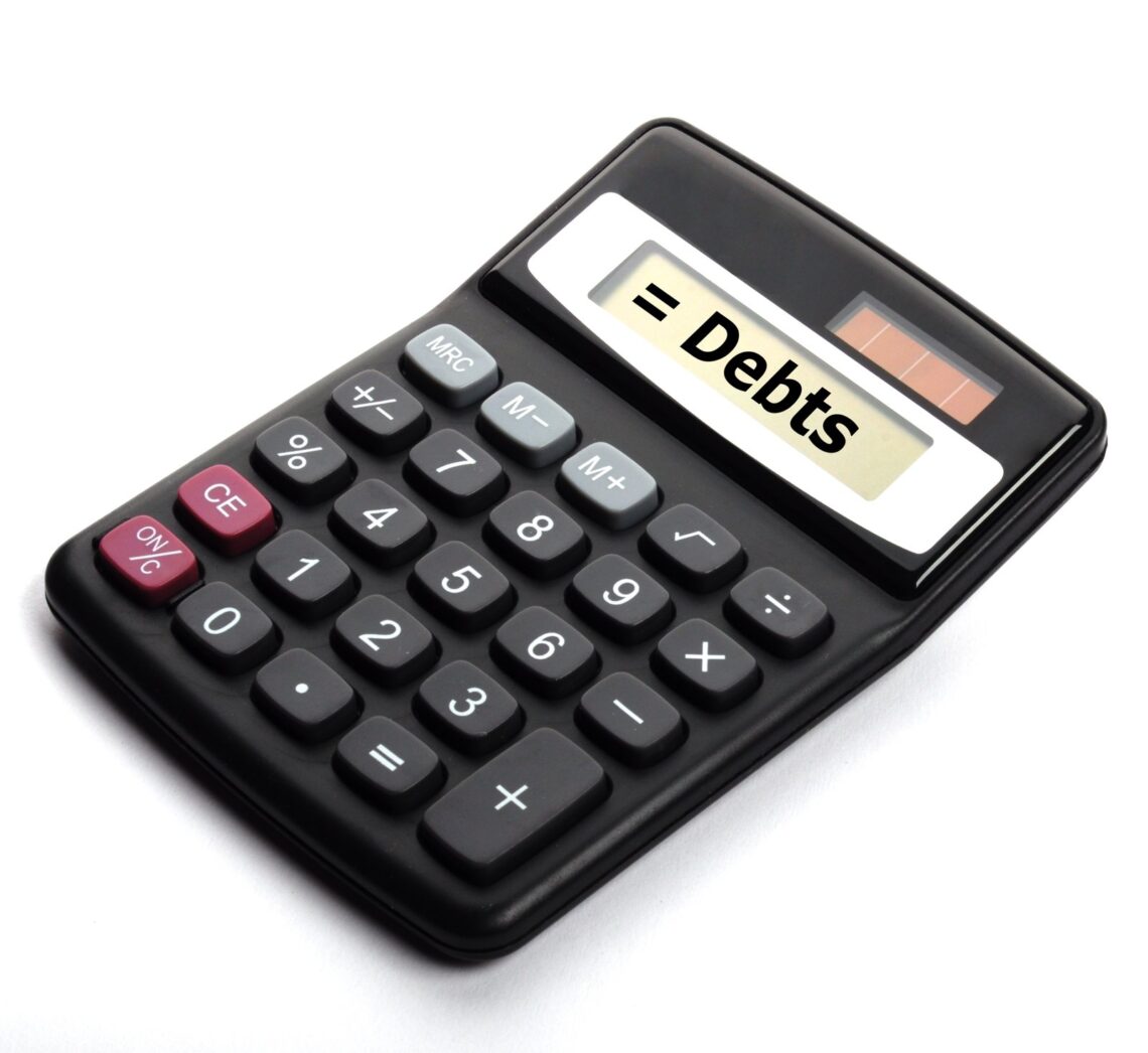 A black solar-powered calculator ominously displays the word "debt" on its screen.