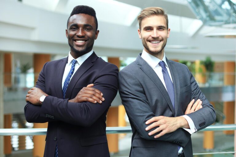 African american and caucasian business partners standing back to back together and looking in camera, in office