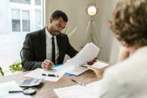 A professional financial advisor reviewing documents with a client, symbolizing the comparison between a CFP vs. financial advisor in guiding financial decisions.