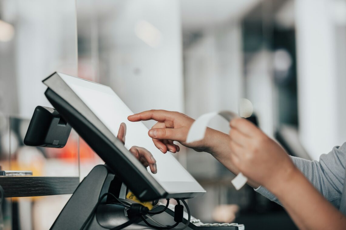 Alternative credit reporting symbolized by a close-up of a person's hands using a touchscreen point-of-sale system while holding a receipt, highlighting modern financial tools and technology integration.