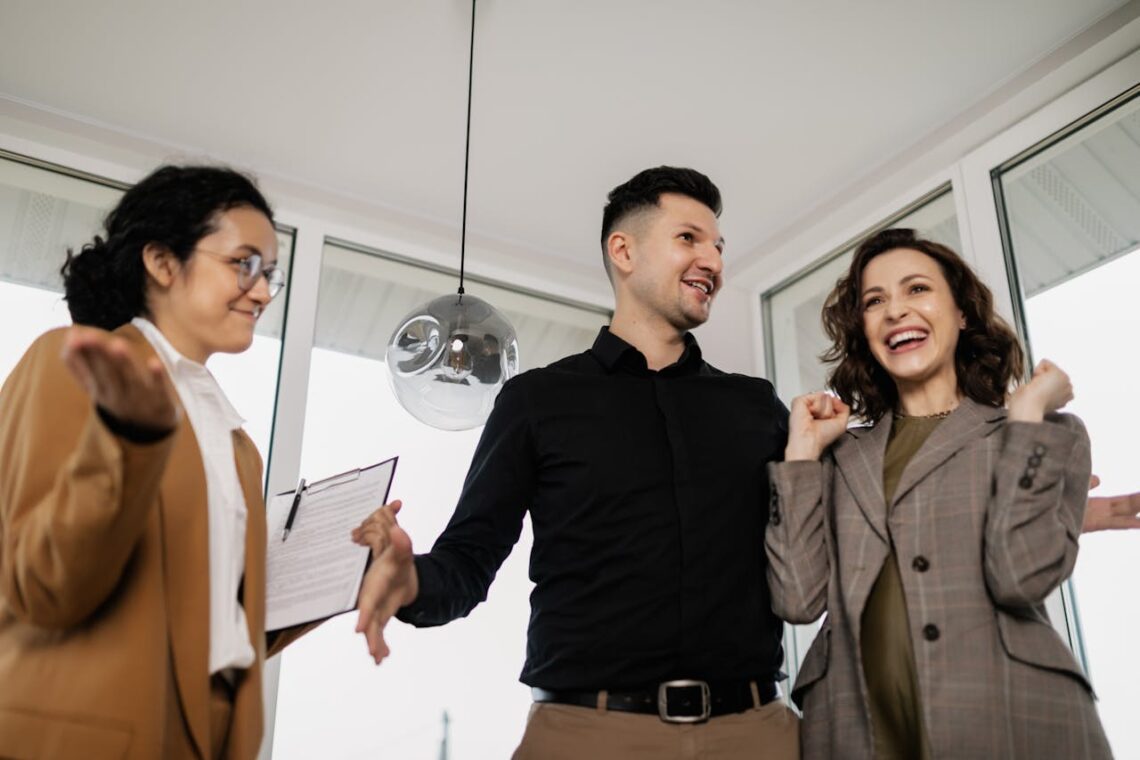 First-time home buyers celebrating their new purchase with a real estate agent, illustrating the success of following essential first-time home buyer tips.