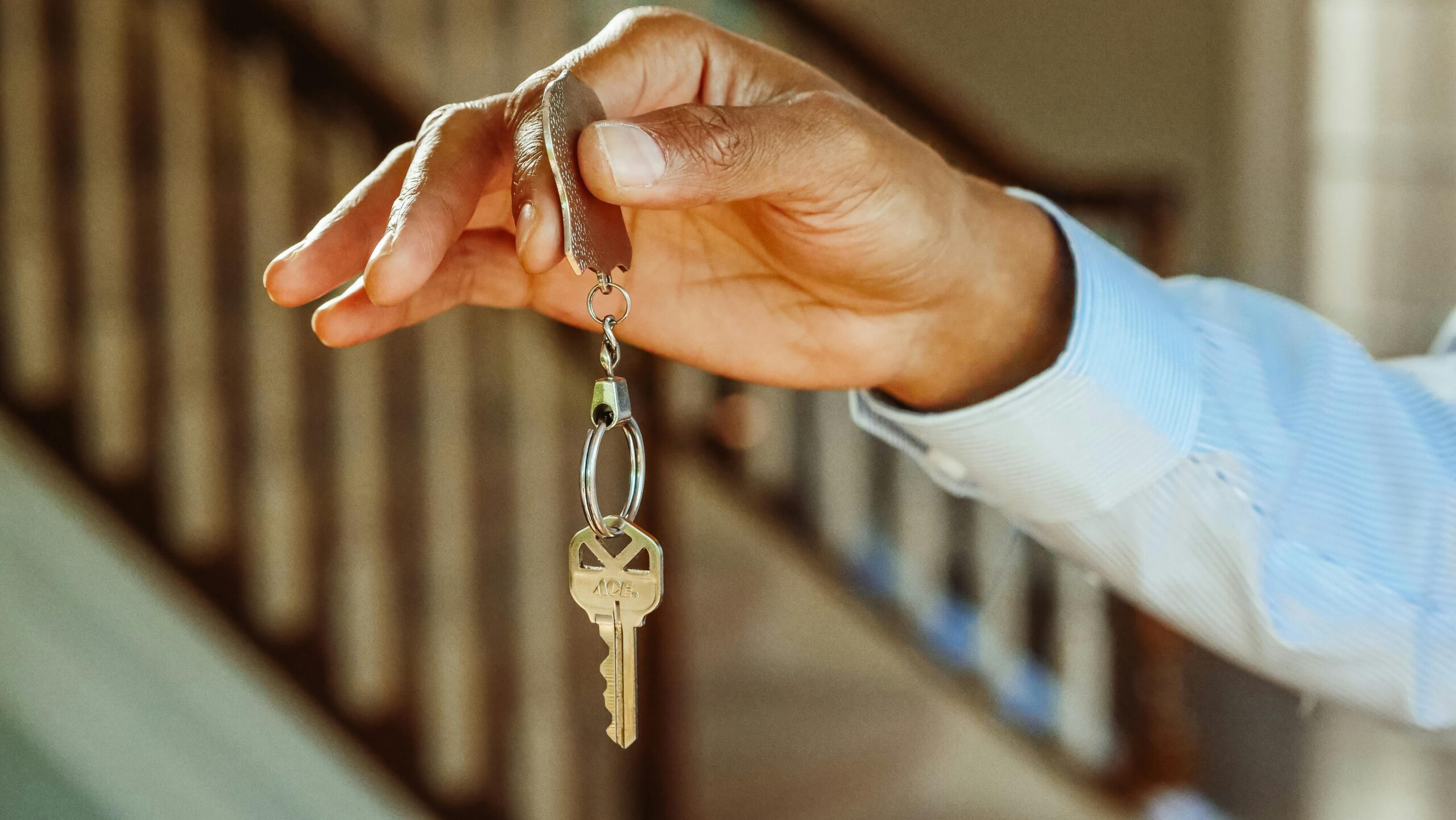 Close-up of a hand holding a house key, symbolizing the concept of rent reporting as a means to build credit through consistent rent payments.