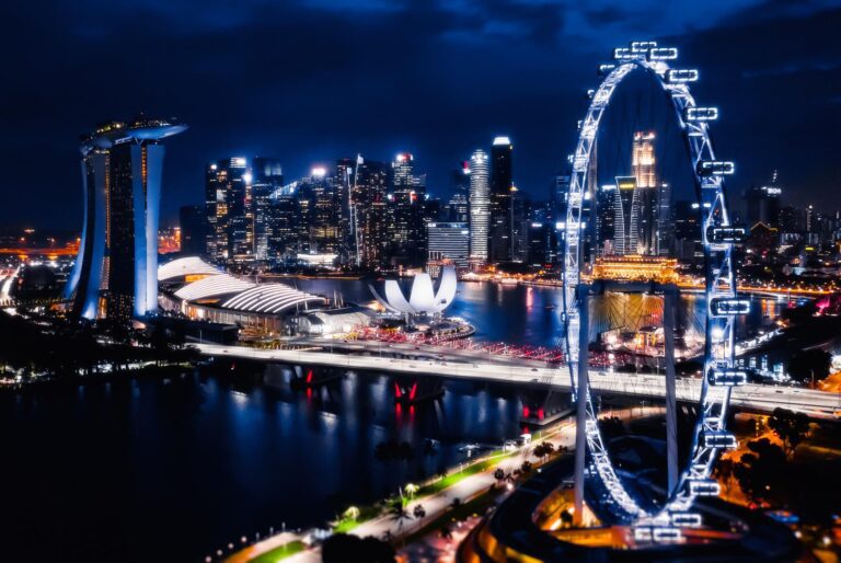 A nighttime cityscape of Singapore featuring the illuminated Marina Bay Sands, the ArtScience Museum, and the Singapore Flyer with reflections on the bay—the perfect backdrop for buying bitcoin in Singapore.