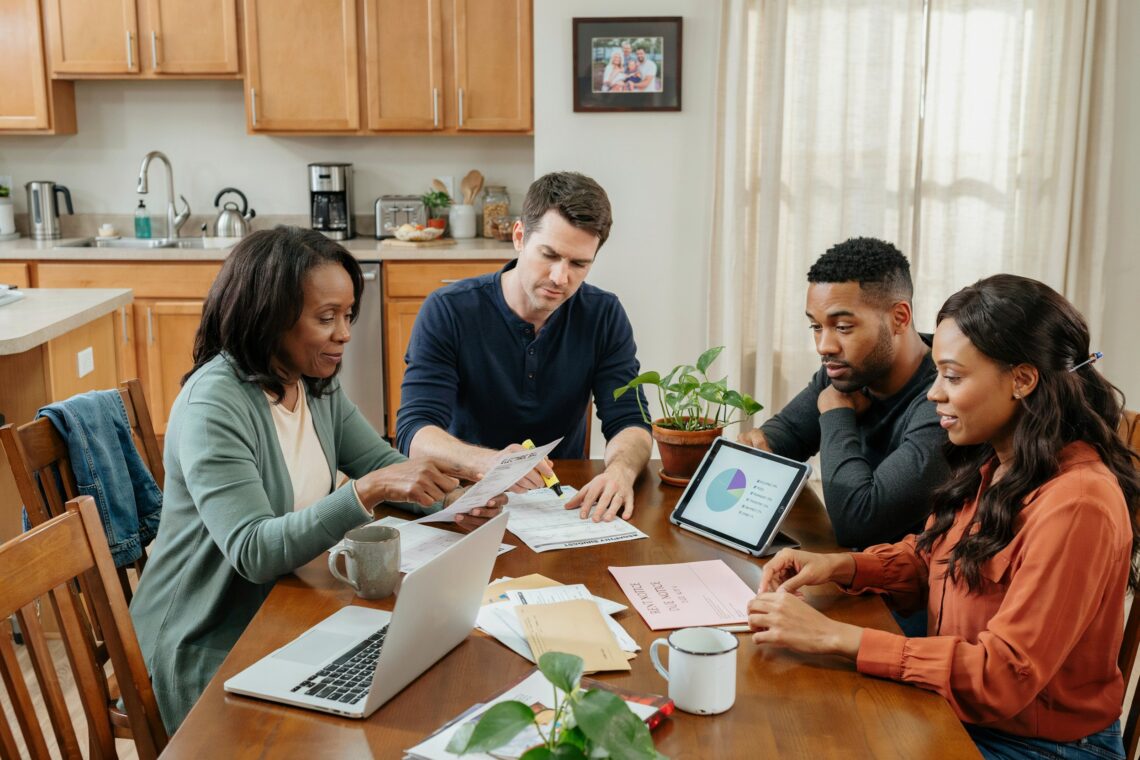 A diverse group of adults reviewing expenses and learning how to prioritize bills during a financial hardship.